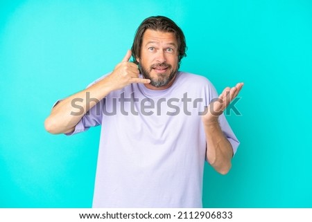 Senior dutch man isolated on blue background making phone gesture and doubting
