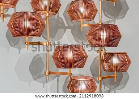 Creative modern chandelier with geometric shaped lampshade and copper details hanging against white wall