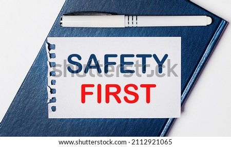 The blue diary lies on a light background. On has a white pen and a piece of paper with the text SAFETY FIRST