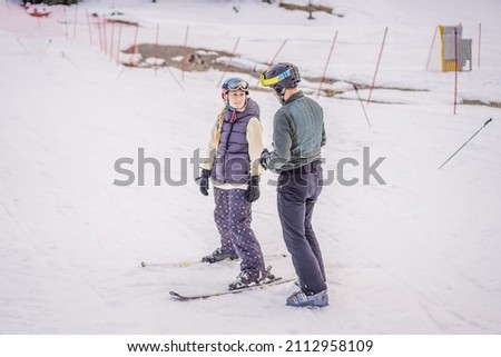 Woman learning to ski with instructor. Winter sport. Ski lesson in alpine school Royalty-Free Stock Photo #2112958109