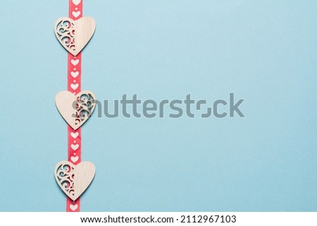 Wooden hearts with a red ribbon in white hearts on a blue background. Background for the holiday of Valentine's Day. The concept of love, romance and tenderness Royalty-Free Stock Photo #2112967103