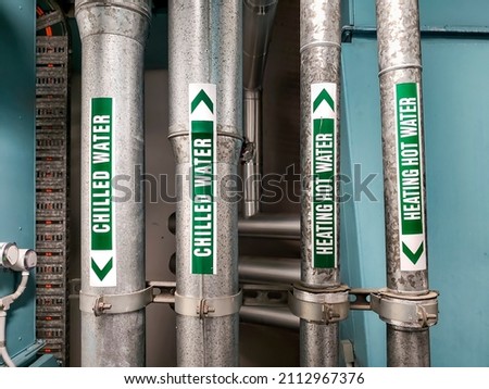 Vertical pipes carrying chilled water and heating hot water that are clearly labeled for safety and maintenance purposes. These can often be seen in commercial buildings and residential complexes.