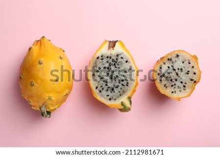 Delicious cut and whole dragon fruits (pitahaya) on pink background, flat lay