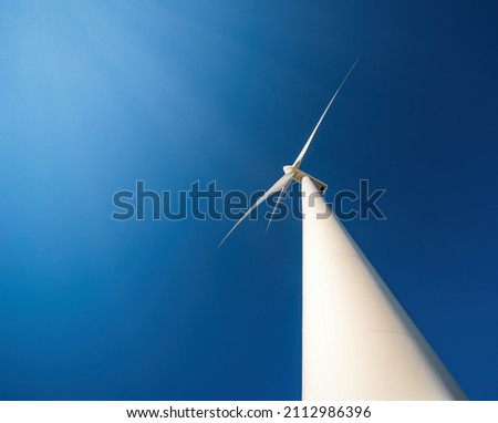 Wind generator against blue sky. Minimalistic shot, low point of view, dramatic perspective
