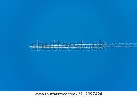 A blue Airliner with white contrails, flying in a clear blue sky, seen directly below, photography.
