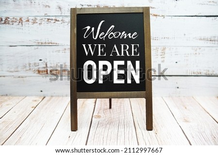 Sign of Welcome We are Open word on blackboard stand on wooden background