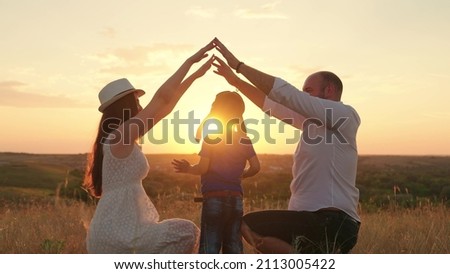 Silhouette of happy family playing shows symbol of comfortable home with their hands at sunset. Teamwork happy family father mother child son dream to buy house. Mortgage lending concept, family home