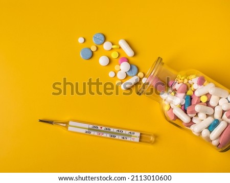Multi-colored pills in a bottle. Yellow background. Virus treatment.