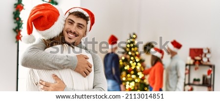 Group of young people on christmas meeting. Couple smiling happy standing and hugging at home.