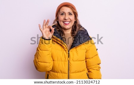 pretty middle age woman feeling happy, showing approval with okay gesture. winter concept