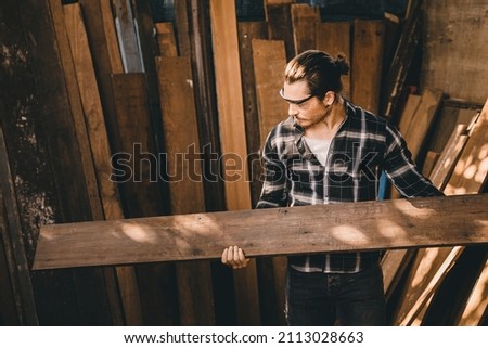 The carpenters man high experienced wood worker making furniture. Master of woodcraft male looking at wood panel. Royalty-Free Stock Photo #2113028663