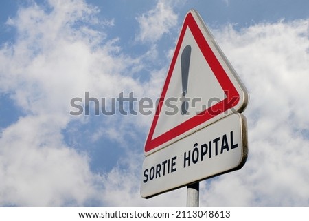 French road sign indicating discharge from hospital on cloudy sky background