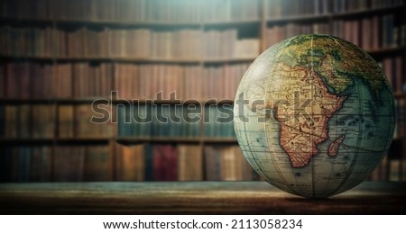 An old globe with Africa on the table against the background of bookcases. Concept on the topic of history, science, culture, education. 