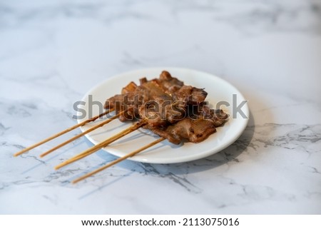 grilled pork in a dish on a marble plate center of picture