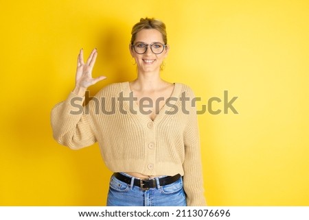 Young beautiful woman wearing casual sweater over isolated yellow background doing hand symbol