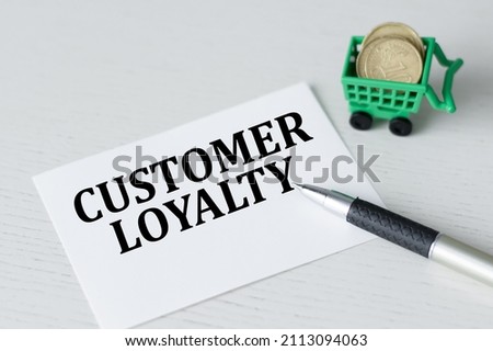 CUSTOMER LOYALTY text on a card on a bright table next to a pen and coins in a green shopping cart