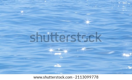 Sun light reflecting or sparkling glitter on water of sea or ocean with beautiful sky blue light tone. Royalty-Free Stock Photo #2113099778
