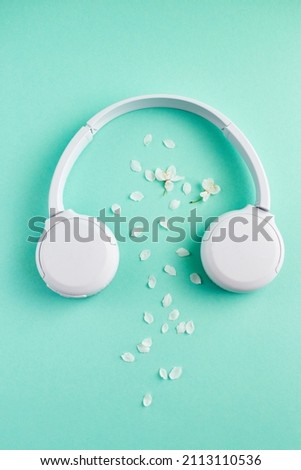 Music or podcast banner with headphones with cherry blossom on turquoise background. flat lay. Top view. Spring playlist concept