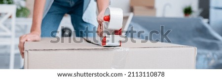 cropped view of woman holding adjusting tape near carton box, banner