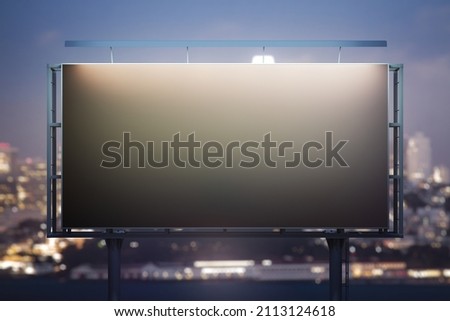 Blank black billboard on cityscape background at evening, front view. Mock up, advertising concept