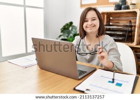 Brunette woman with down syndrome working using laptop at business office Royalty-Free Stock Photo #2113137257