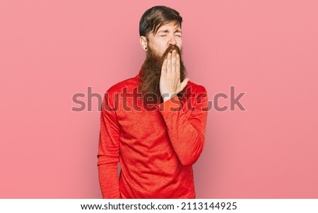 Redhead man with long beard wearing casual clothes bored yawning tired covering mouth with hand. restless and sleepiness. 