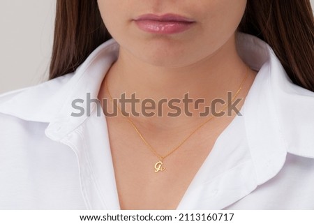 Gold initial necklace on neck of attractive white dress girl. Personalized necklace image. Jewelry photo for e commerce, online sale, social media.
