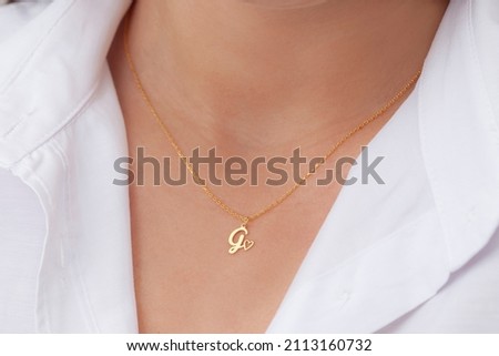 Gold initial necklace on neck of attractive white dress girl. Personalized necklace image. Jewelry photo for e commerce, online sale, social media. Royalty-Free Stock Photo #2113160732