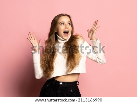 Wow emotions. Portrait of surprised young beautiful smiling girl in warm white sweater isolated on pink background. Concept of emotions, facial expression, youth, aspiration, sales.