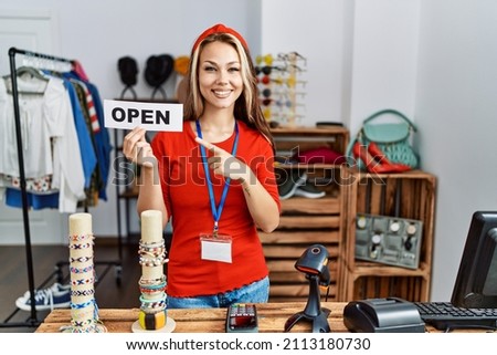 Young caucasian woman holding banner with open text at retail shop smiling happy pointing with hand and finger 