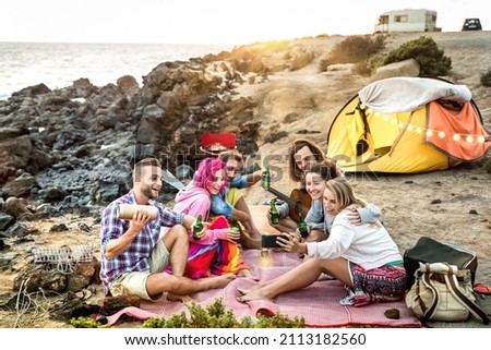 Hipster people taking selfie at beach camping party - Wanderlust travel life style concept with happy friends travelers cheering together with beer and guitar at summer surf camp - Warm sunset filter