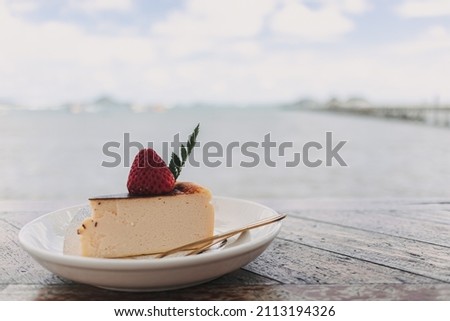 Burnt Cheese Cake with strawberry on top served on wooden table.