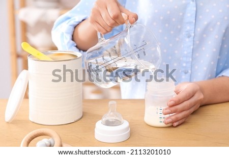 Woman preparing infant formula at table indoors, closeup. Baby milk Royalty-Free Stock Photo #2113201010