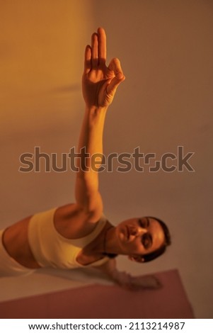 young woman doing yoga poses in studio on white background, sunset light