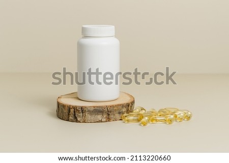 Mockup medical bottle on wooden stand with fish oil capsules, organic supplement, natural vitamin capsules , beige background Royalty-Free Stock Photo #2113220660