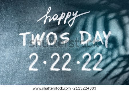 Happy Twos Day 2.22.22 vector concept. White chalk lettering on scholboard background with palm leaves shadows. February 2nd, 2022 is such an significant date. Royalty-Free Stock Photo #2113224383