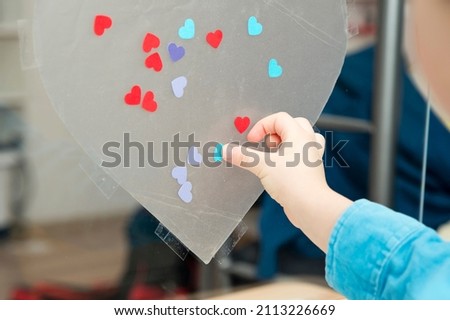 Heart for mothers day. Kid sticking colored paper hearts to adhesive tape. Festive decoration. Womens, Wedding, Happy st Valentines Day concept, 14th February.