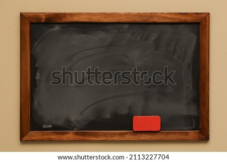 Dirty black chalkboard hanging on beige wall