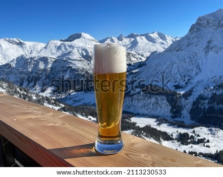Apres ski in the Austrian Alps. Glass of wheat beer on wooden fence on a sunny day. Lech Zuers skiing resort, part of the Arlberg skiing area. High quality photo