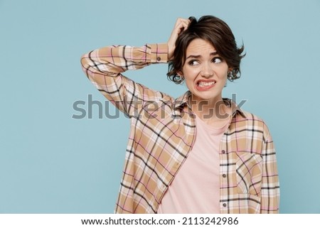 Young mistaken sad puzzled woman 20s wearing casual brown shirt look aside scratch hold head say oops isolated on pastel plain light blue color background studio portrait. People lifestyle concept. Royalty-Free Stock Photo #2113242986