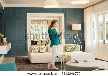 Woman texting with cell phone in home showcase living room
