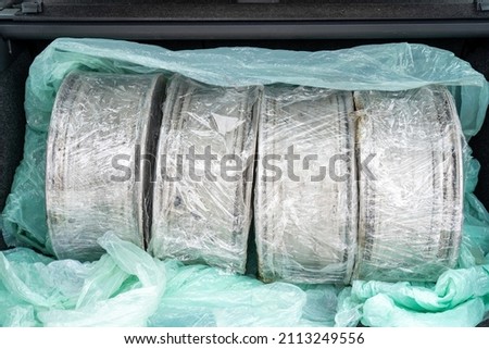 Closeup view stock photography of opened car boot and four old used steel wheel rims bought online through internet. Driver just received them in post office of delivery service