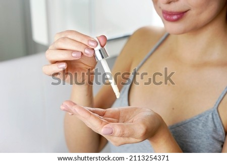 Beautiful woman holding a pipette in her hand with serum moisturizing anti aging antioxidant. Focus on hand. Royalty-Free Stock Photo #2113254371