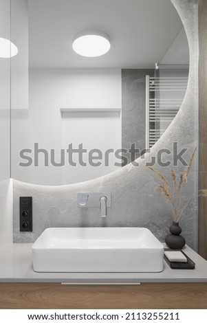 Big, round mirror over stylish washbasin in modern bathroom Royalty-Free Stock Photo #2113255211