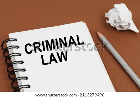 Business and finance concept. On a brown surface lies a pen, crumpled paper and a notepad with the inscription - CRIMINAL LAW Royalty-Free Stock Photo #2113279490