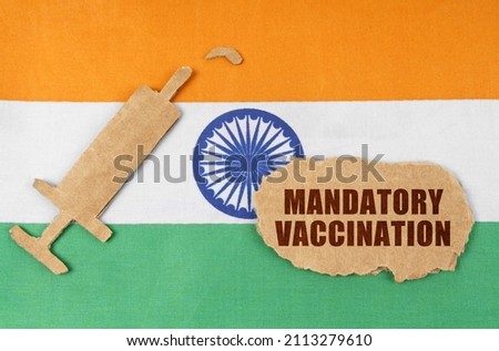Medical concept. On the flag of India, a cardboard figure of a syringe and a torn cardboard with the inscription -