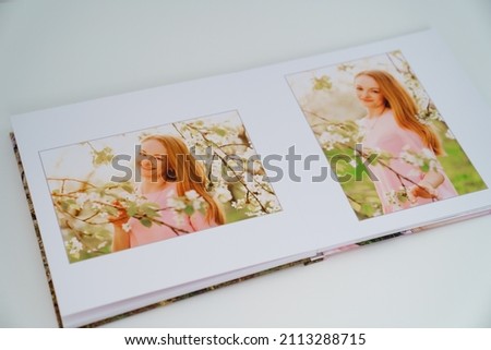 on white background, an open photobook with a photo of an attractive woman in spring garden. Tradition print photo album and review and remember moments of life. services of photographer and designer