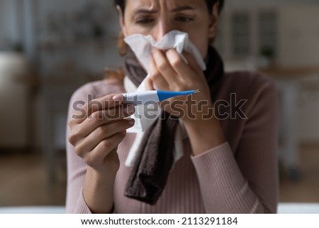 Unhealthy young woman holds tissue blow runny nose use thermometer measure temperature, suffer from influenza flu or cold, have COVID-19 or new delta strain symptoms, close up. Corona virus concept Royalty-Free Stock Photo #2113291184