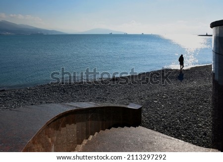 Sea. Mountains. Dawn. A man admires the play of the rays of the sun on the water. Bokeh light. Blurred background of the concept of the seascape.