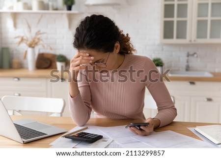 Latina woman sit in kitchen check personal finances, calculate domestic bills feels stressed, think about pay off rent debt. Financial problem, budget manage, overspend, high taxes, bankruptcy concept Royalty-Free Stock Photo #2113299857